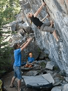 A person boulding while two others are spotting him.