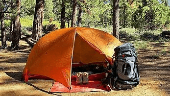 Orange Tent set up with camping equipment at a campsite