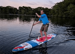 A person paddleboarding on a calm lake.